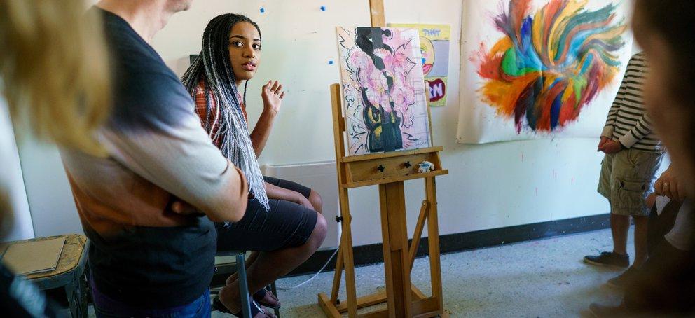 a student is presenting her painting in front of an art class